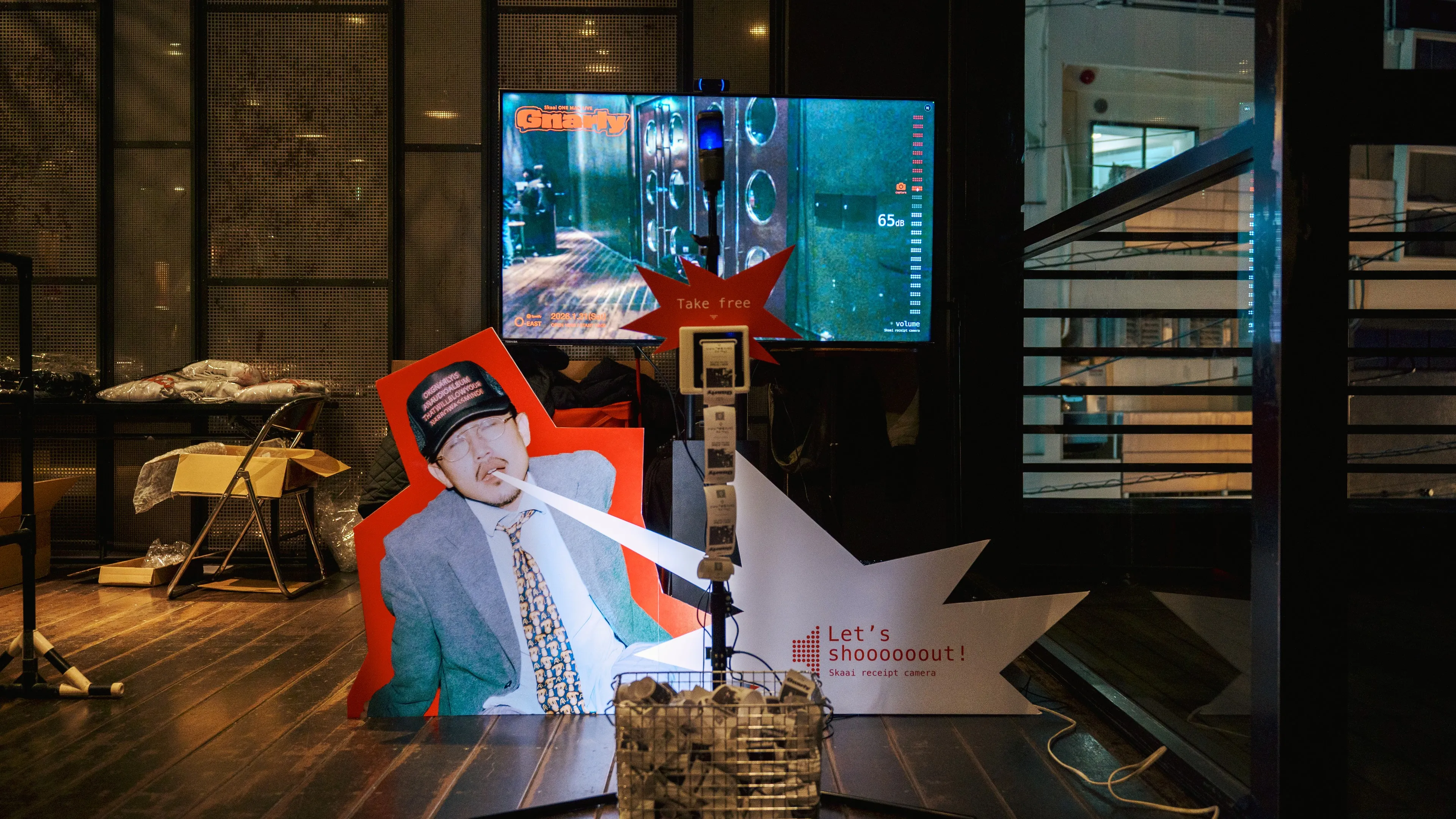 ライブ会場に置かれた Shout Camera のブース。モニター、マイク、レシートの出る機械と、叫ぶ人のパネル