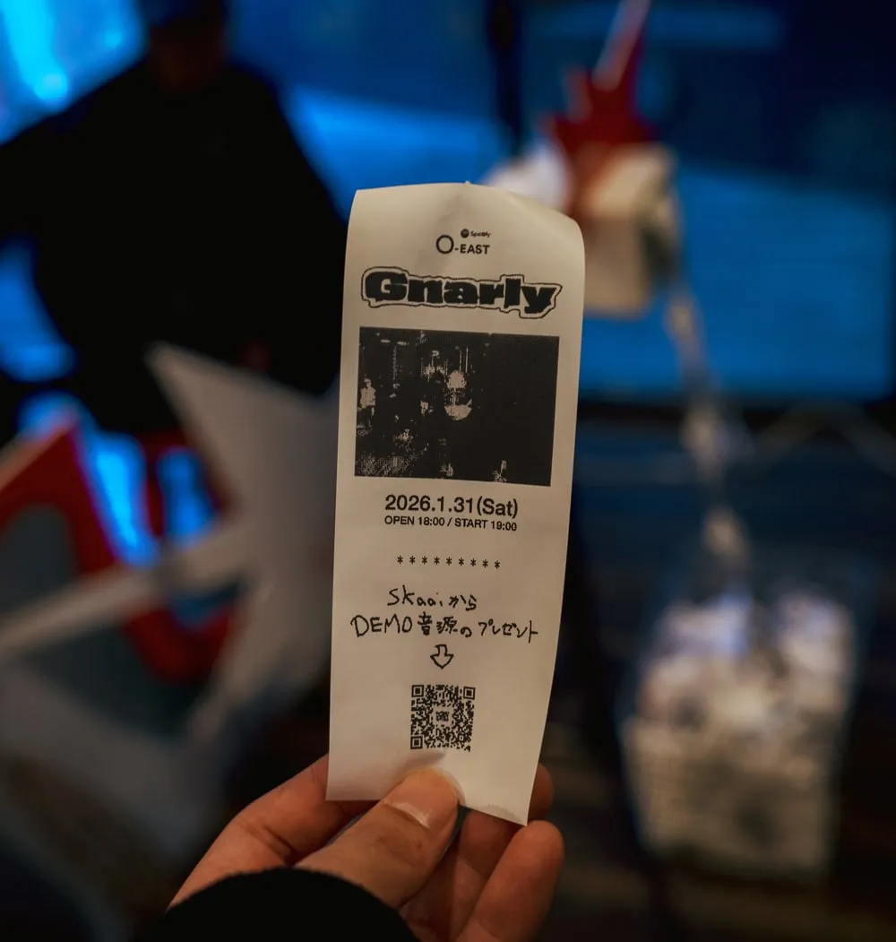 写真と QR コードが印刷されたレシートを手に持っている